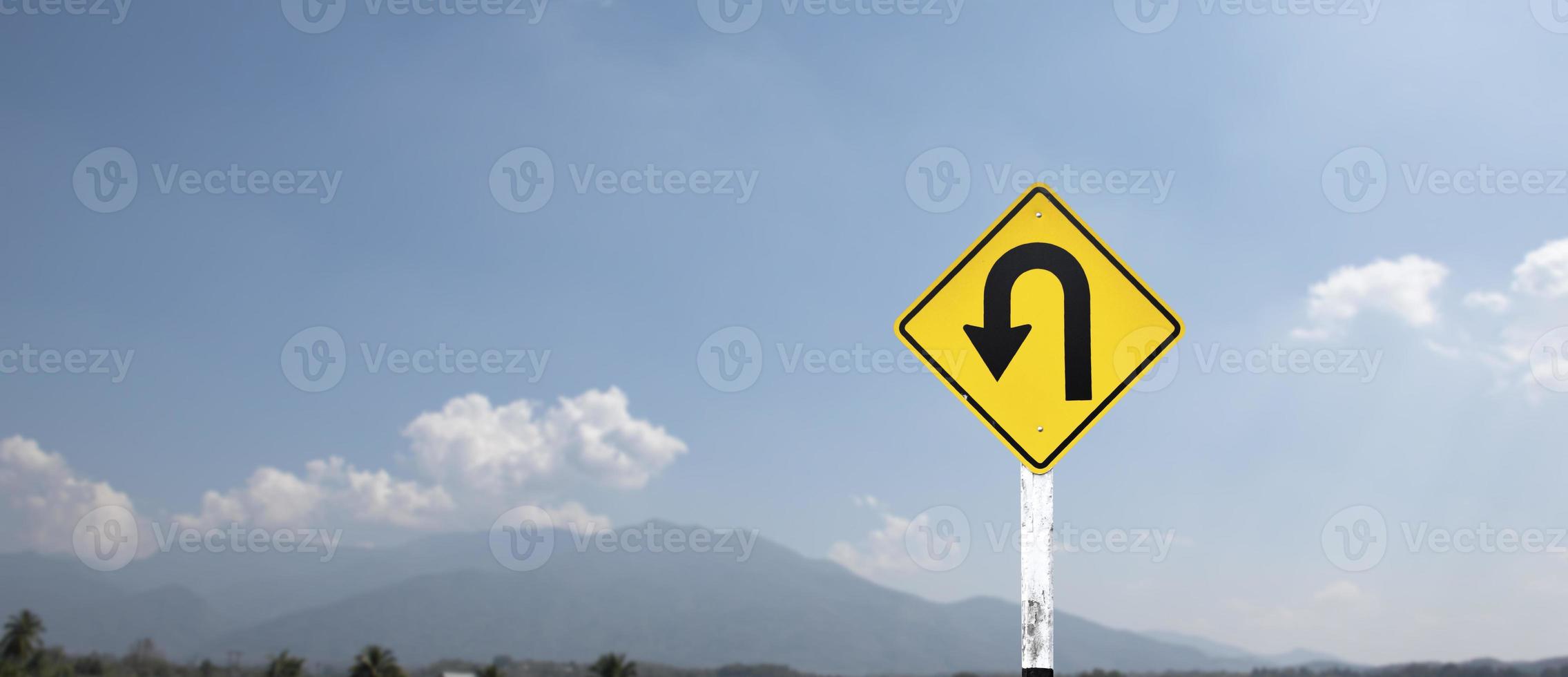 Traffic sign, left U turn sign on cement pole beside the rural road with white cloudy bluesky background, copy space. photo