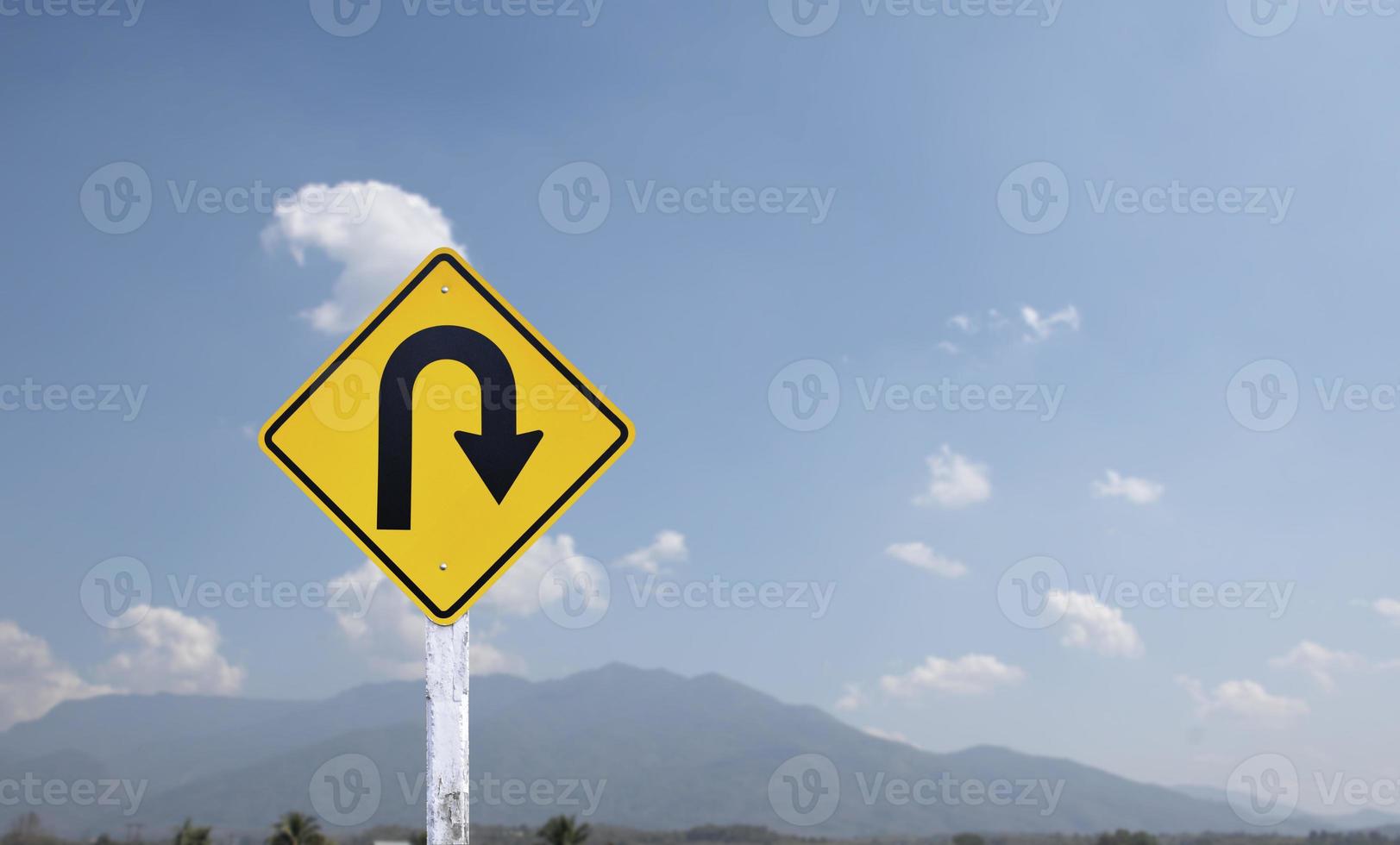 Traffic sign, right U turn sign on cement pole beside the rural road with white cloudy bluesky background, copy space. photo