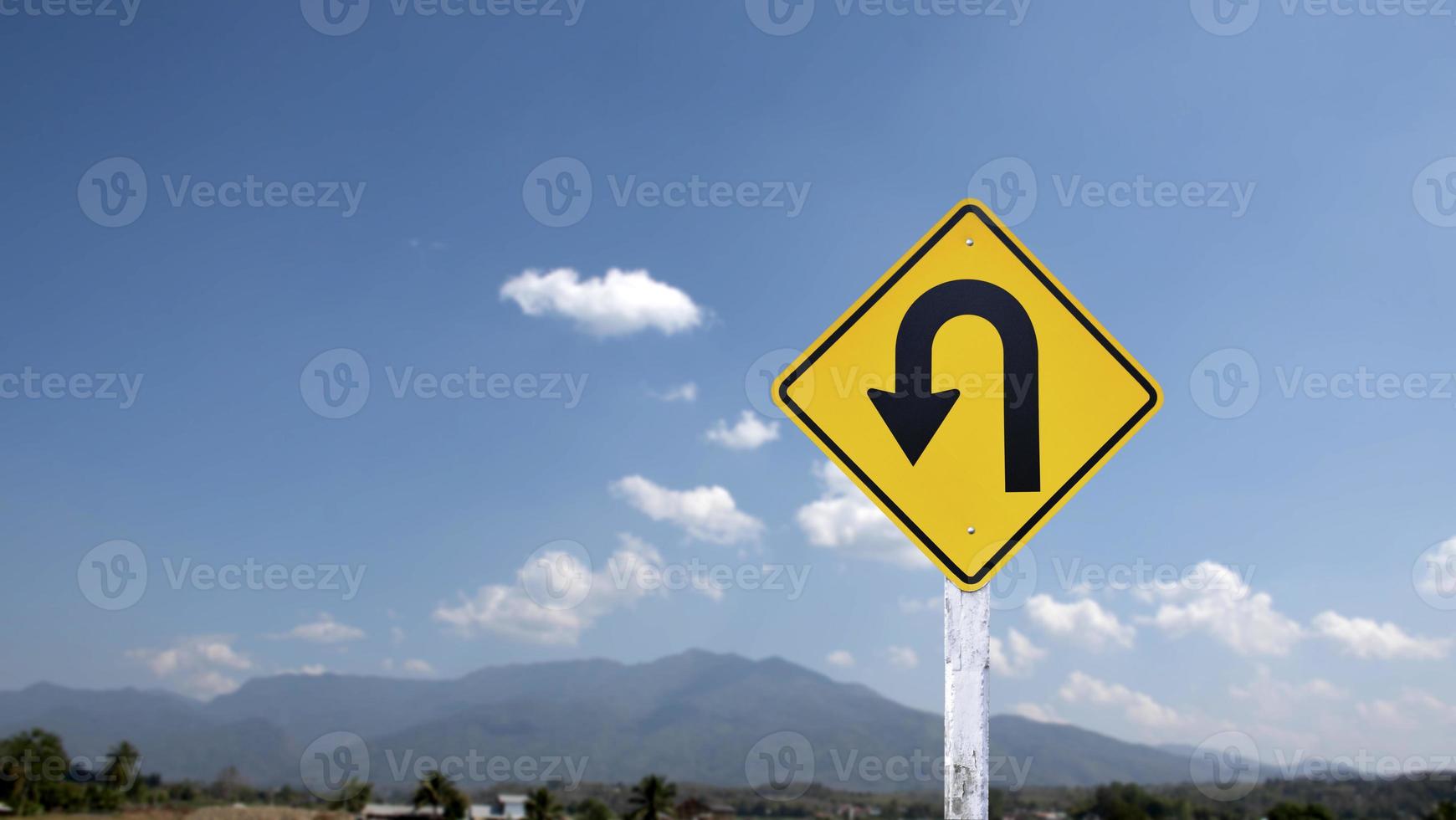 Traffic sign, left U turn sign on cement pole beside the rural road with white cloudy bluesky background, copy space. photo