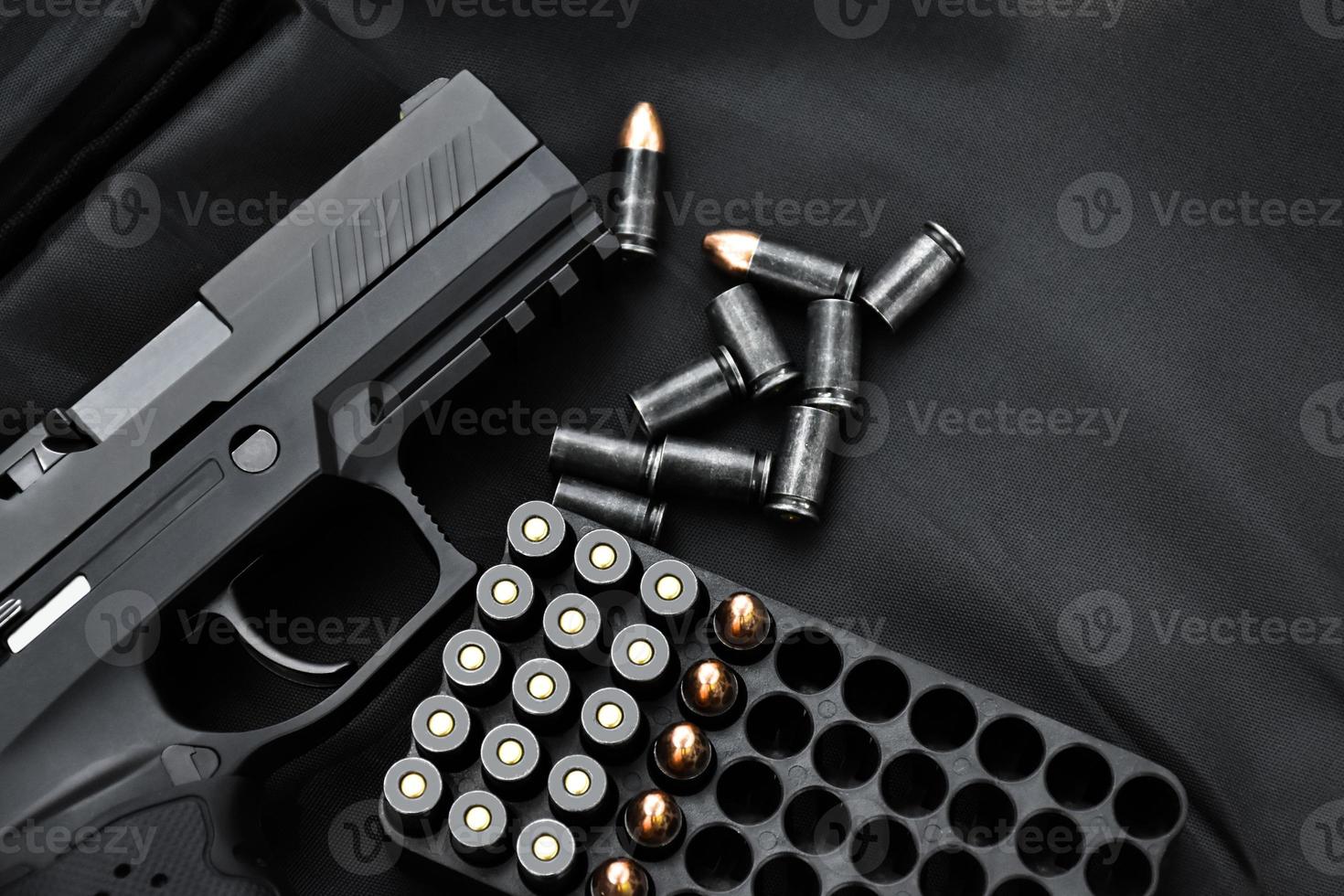 Automatic black 9mm pistol and bullets on black leather background, selective and soft focus, copy space. photo