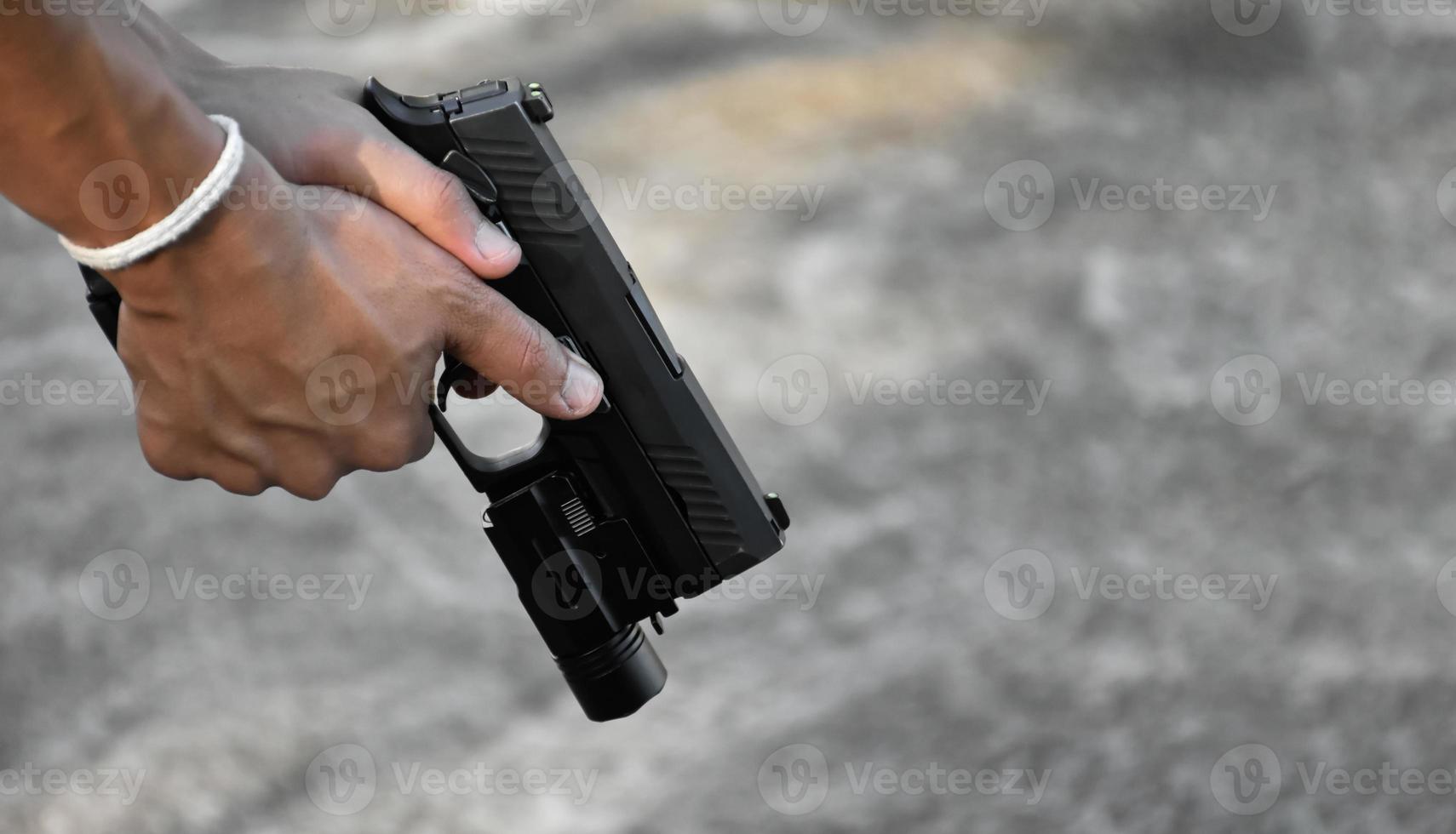Pistola automática de 9 mm sujeta en la mano derecha del tirador, concepto de seguridad, robo, gángster, guardaespaldas en todo el mundo. enfoque selectivo en pistola. foto