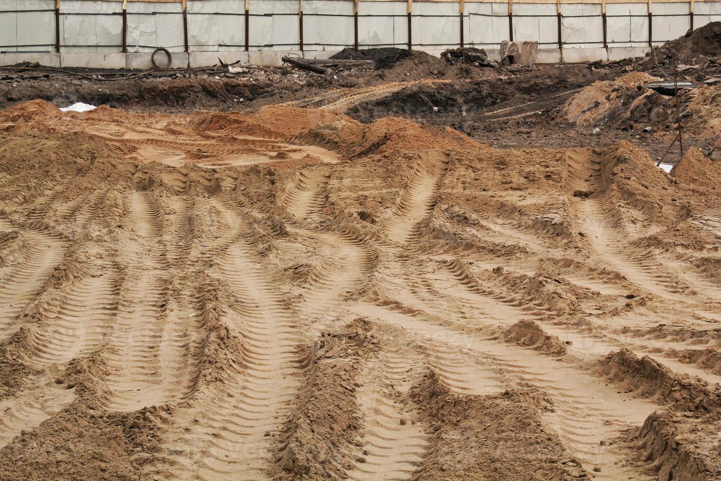 Tire track mark lines shape on dry sand background. Trail tyre imprint from heavy machinery. Vehicle shape. Road construction site backdrop concept. Trace of wheel pattern on mud. Nature texture. photo