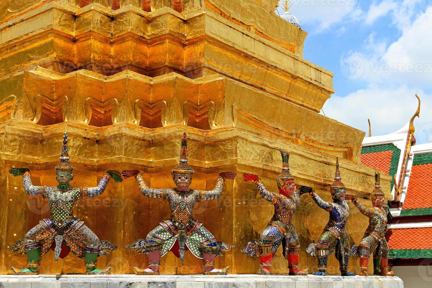 The ramayana giant statues are standing with big golden pagoda background at Wat Ph-ra Kaew Ancient temple in Bangkok, Thailand. Landmark in Center of Thailand and Art design. Exterior and structure. photo