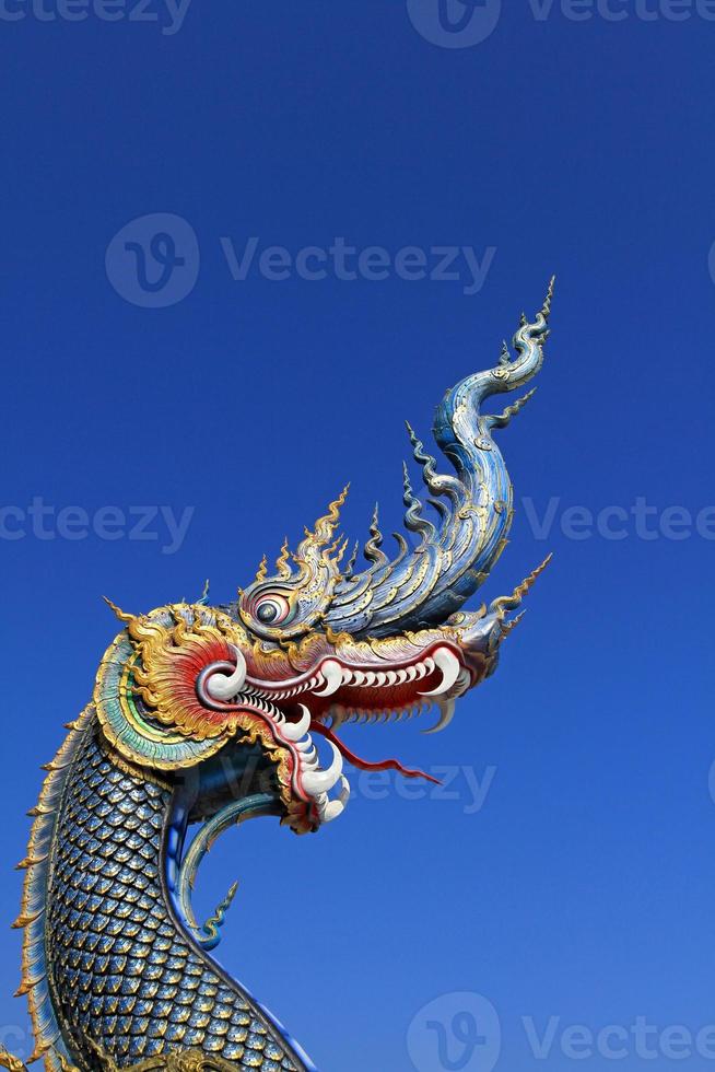 Blue head of Naka or serpent statue opening mouth with clea blue sky background and copy space on above at Wat Rong Sua Ten at Chiang Rai, Thailand. Buddhist Temple and Exterior structure design. photo