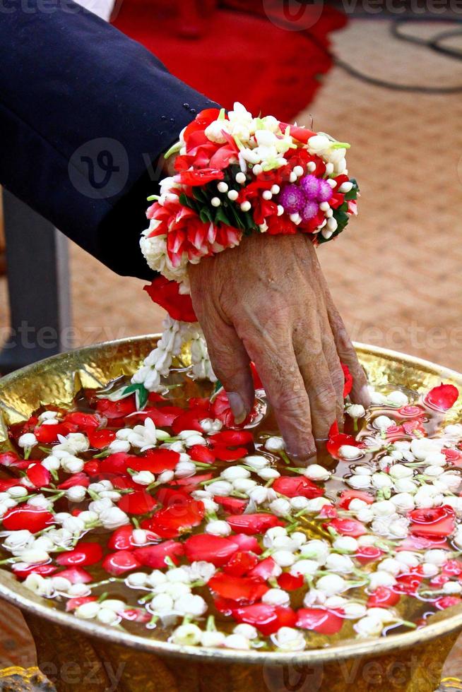 Watering funeral ceremony of dead people in Thailand. Close up body part of human with jasmine, red rose flower petal on water. Asian Ritual, Ceremony or worship photo