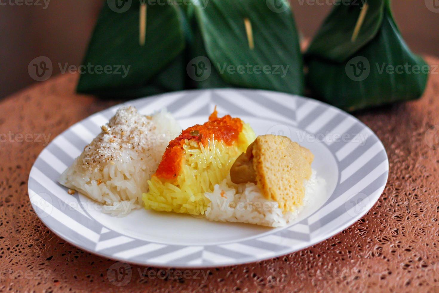 3 flavors Thai desserts, sticky rice, custard topped with dried fish and yellow sticky rice, wrapped in banana leaves photo