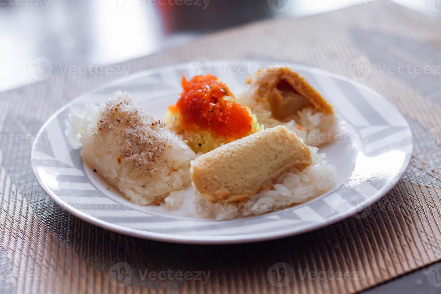 3 flavors Thai desserts, sticky rice, custard topped with dried fish and yellow sticky rice, wrapped in banana leaves photo