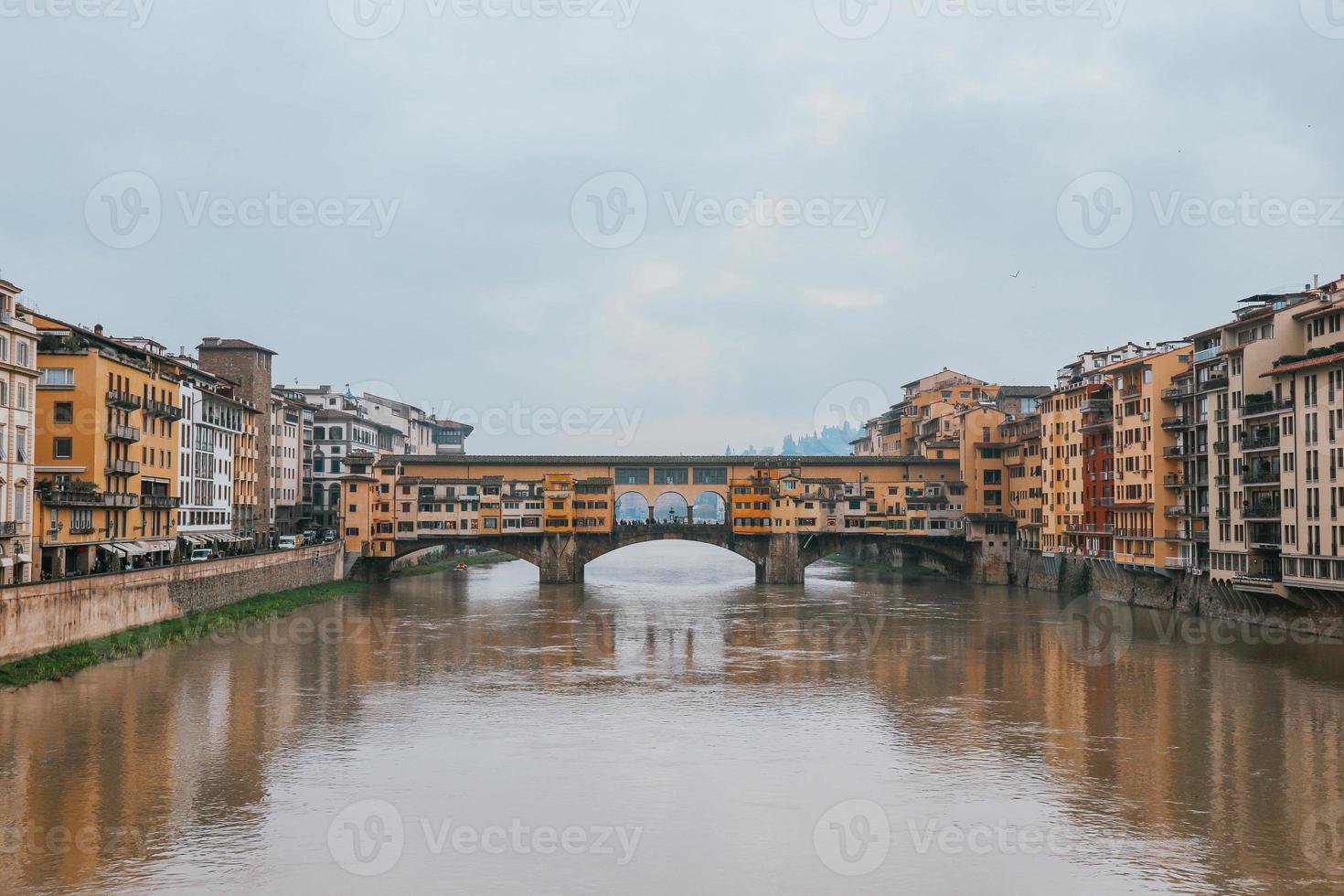 Front symmetrical view old town medieval bridge over gloomy waters and colorful buildings photo