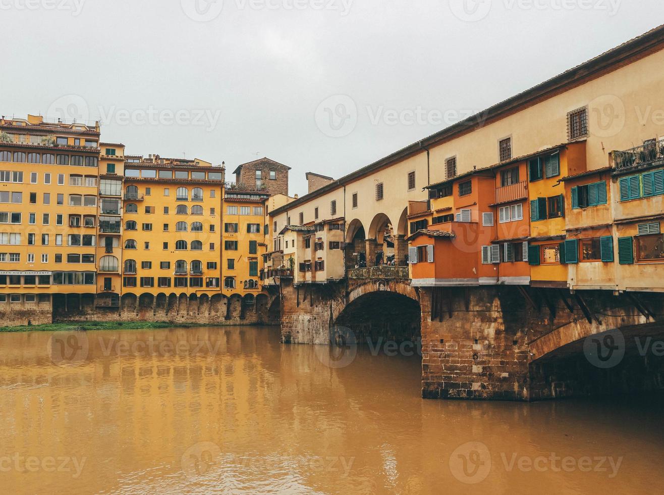 Detail of old town medieval bridge over gloomy waters and yellow buildings photo