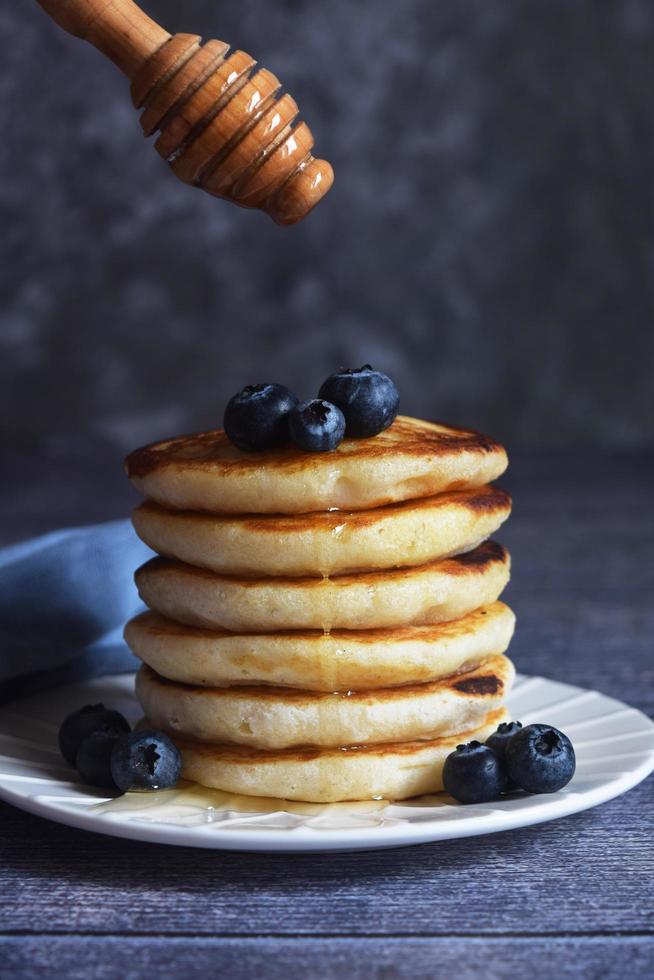 a stack of pancakes with blueberries and a spoon with honey photo