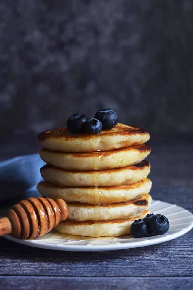 a stack of pancakes with blueberries and a spoon with honey photo