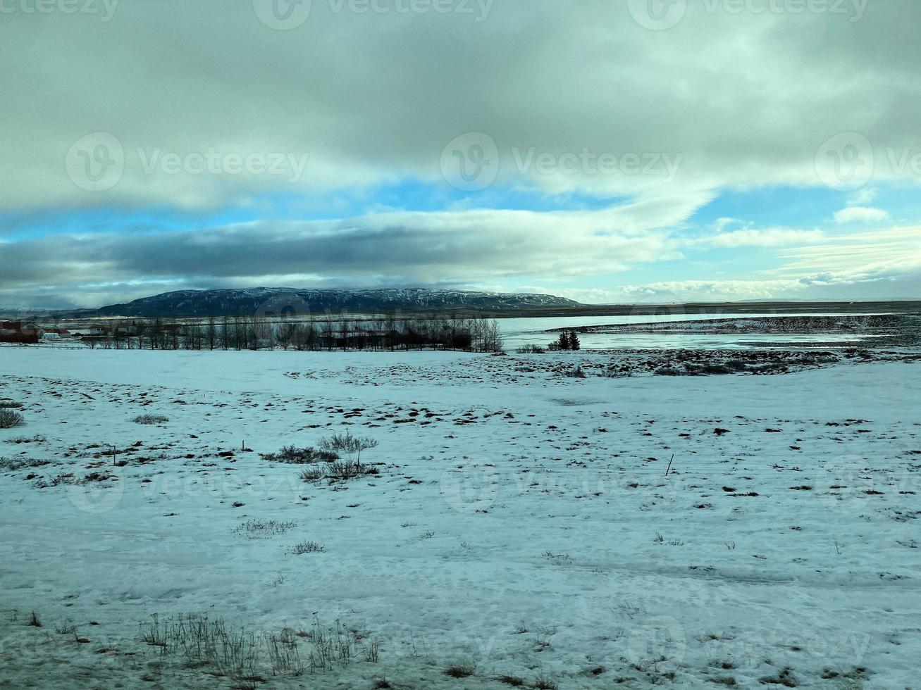 Icelandic winter landscape with snow covered hills and blue cloudy sky photo