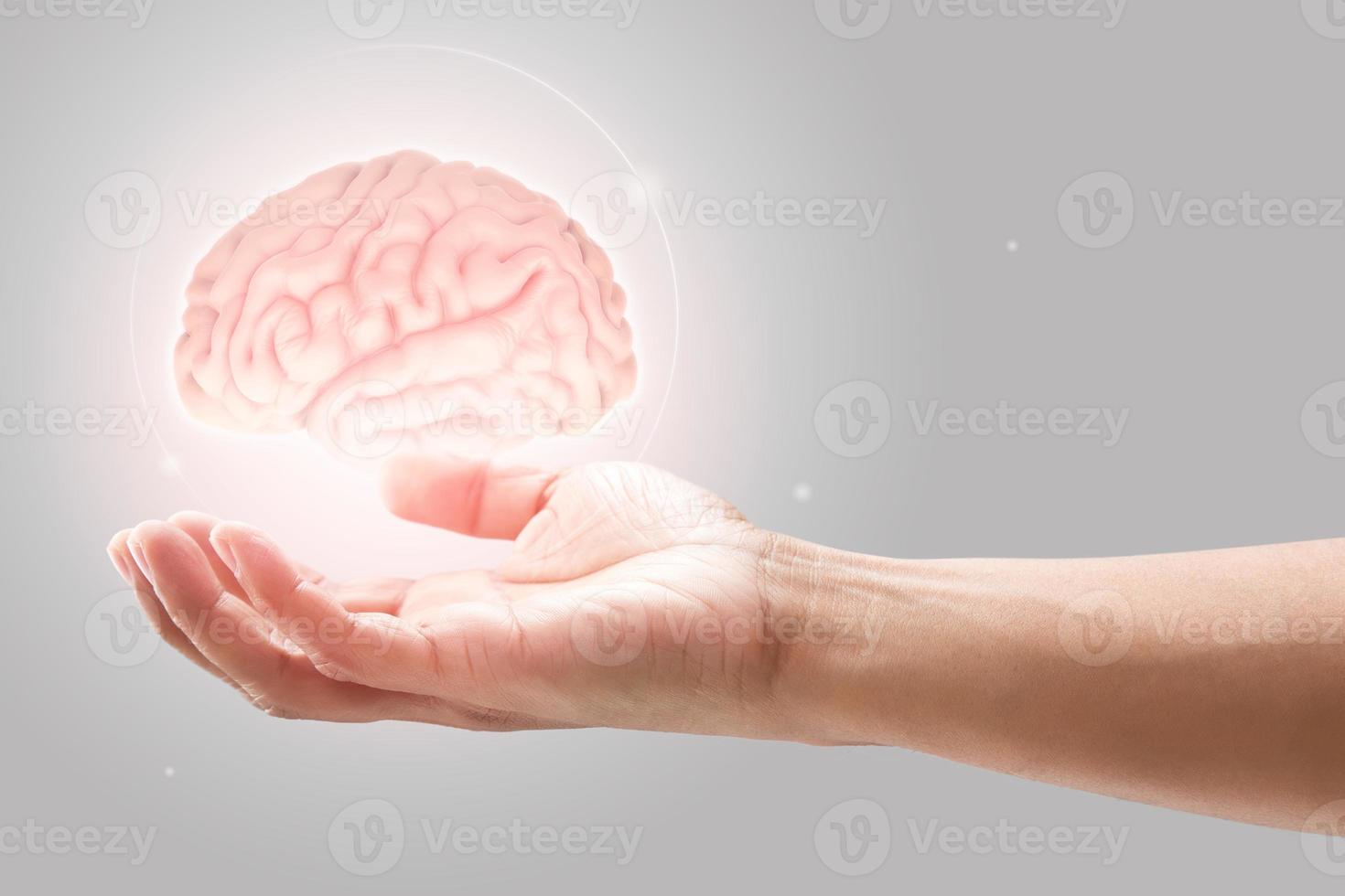 Man holding brain illustration against gray wall background. Concept with mental health protection and care. photo