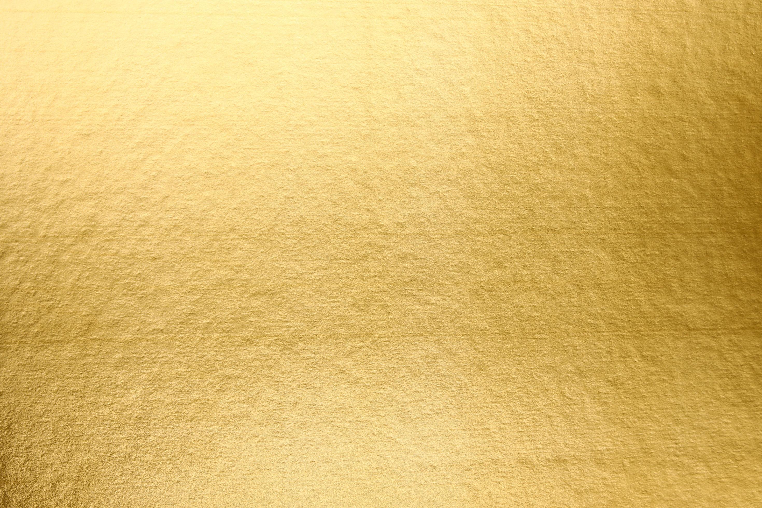 A gold paper that is textured and has a light shining on it. golden
