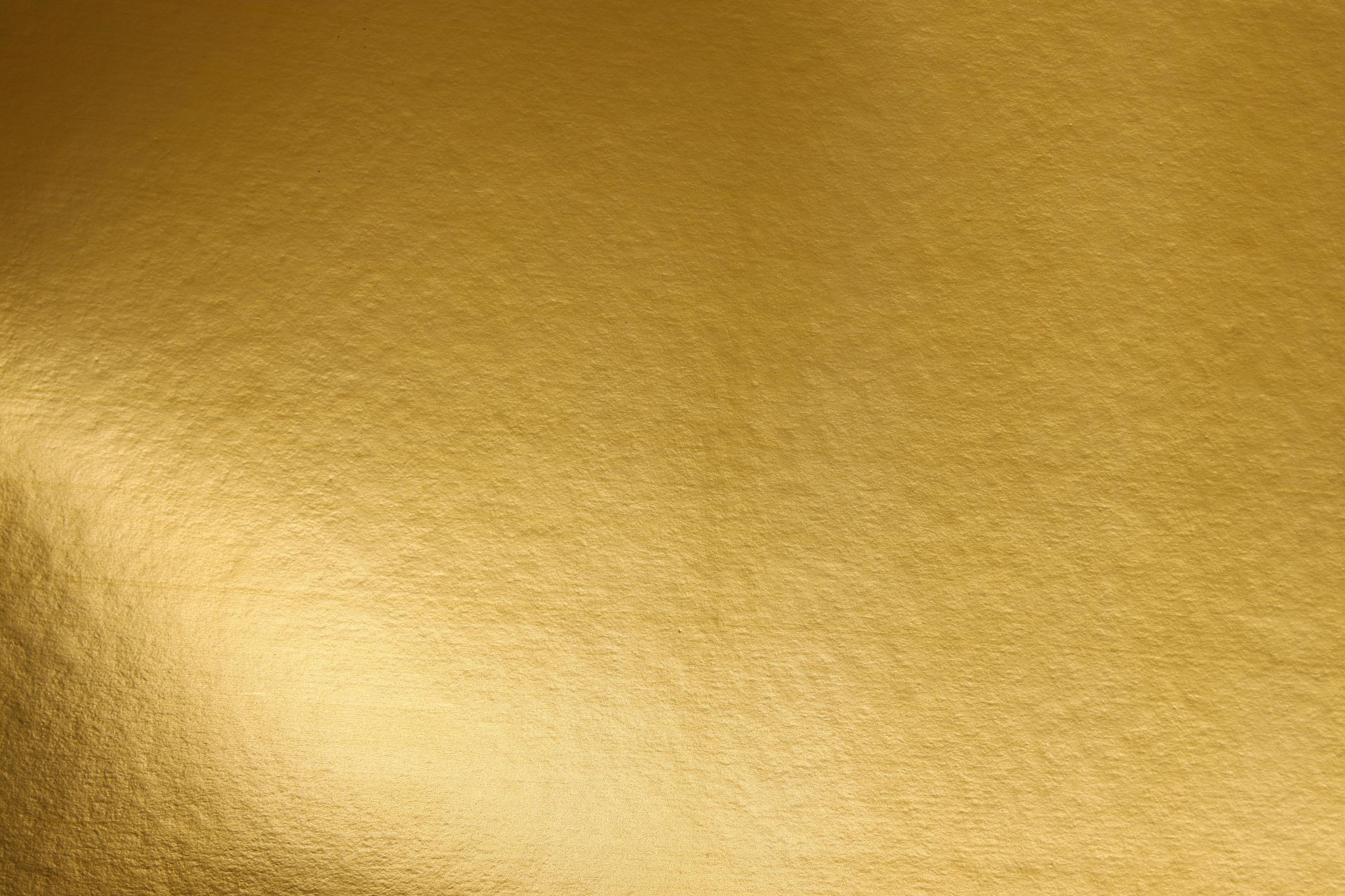 A gold paper that is textured and has a light shining on it. golden