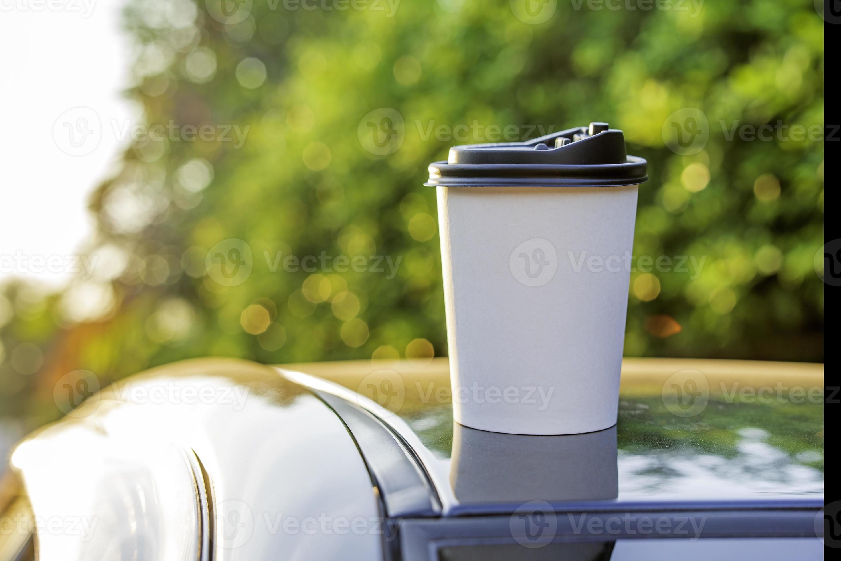 White paper coffee Cup with red lid on car roof. Paper Cup with hot tea on  the roof of the SUV close up on the background of the windshield Stock  Photo