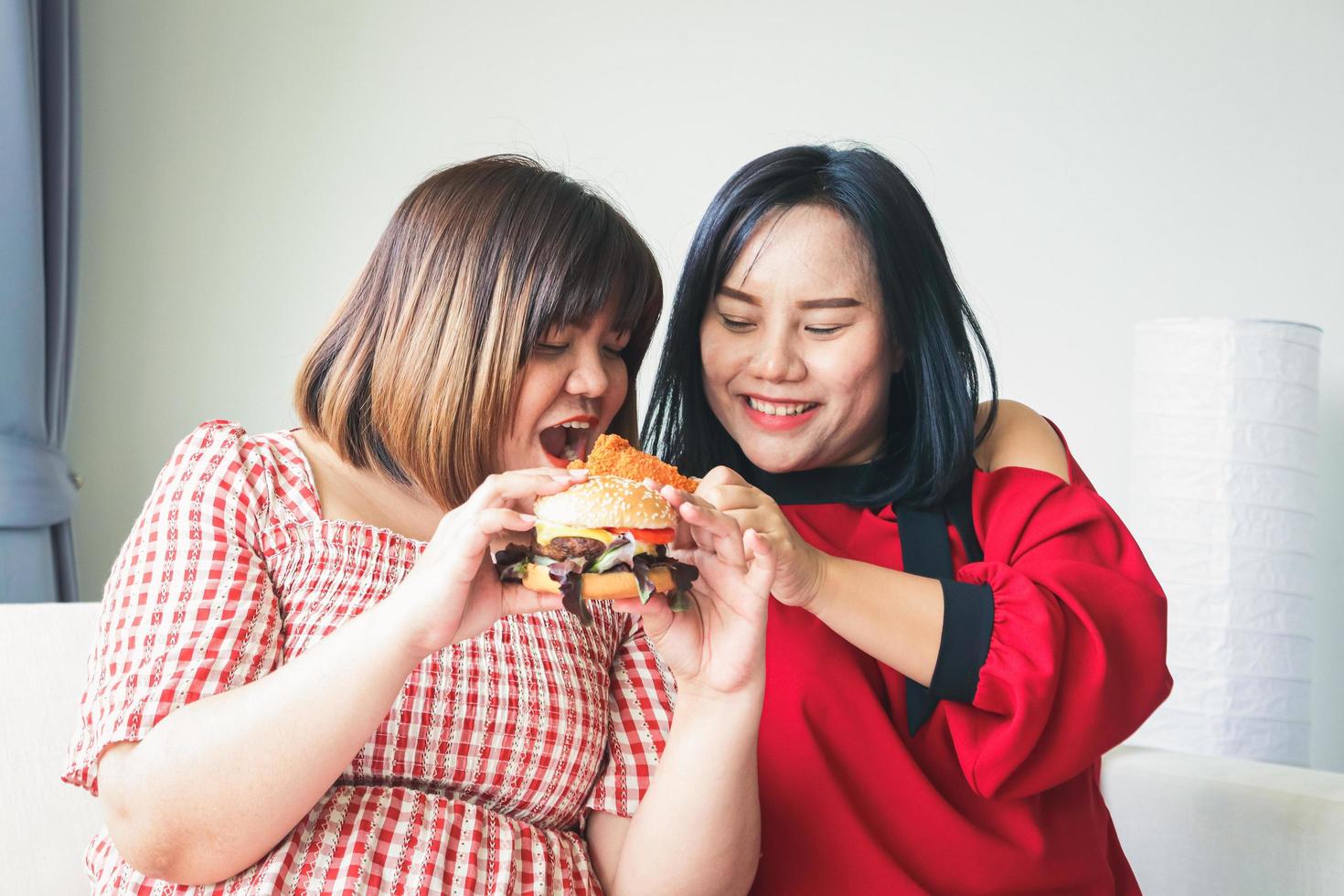 dos grasa mujer, asiáticos, comer un grande hamburguesa. salud conceptos exceso de peso personas foto