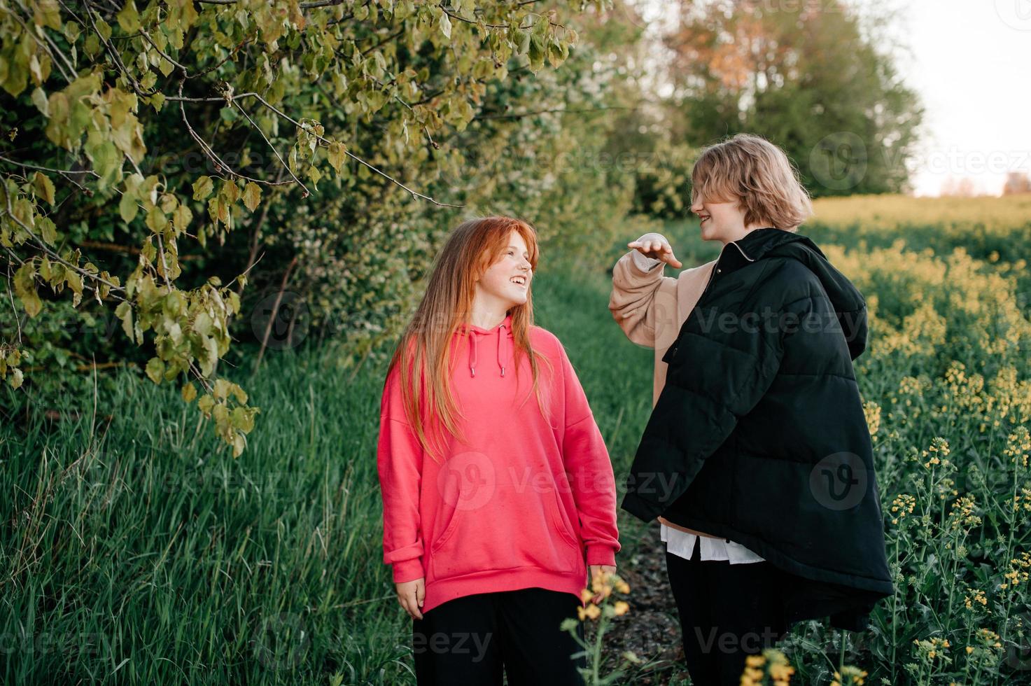 Two teenage girls are hugging at sunset and laughing photo