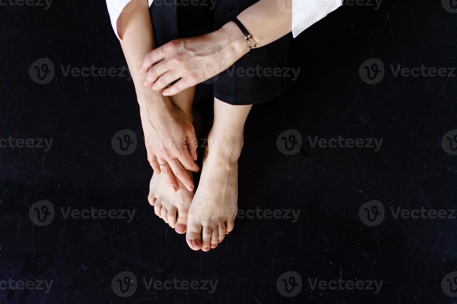 A man is sitting on a black floor. Arms and legs photo