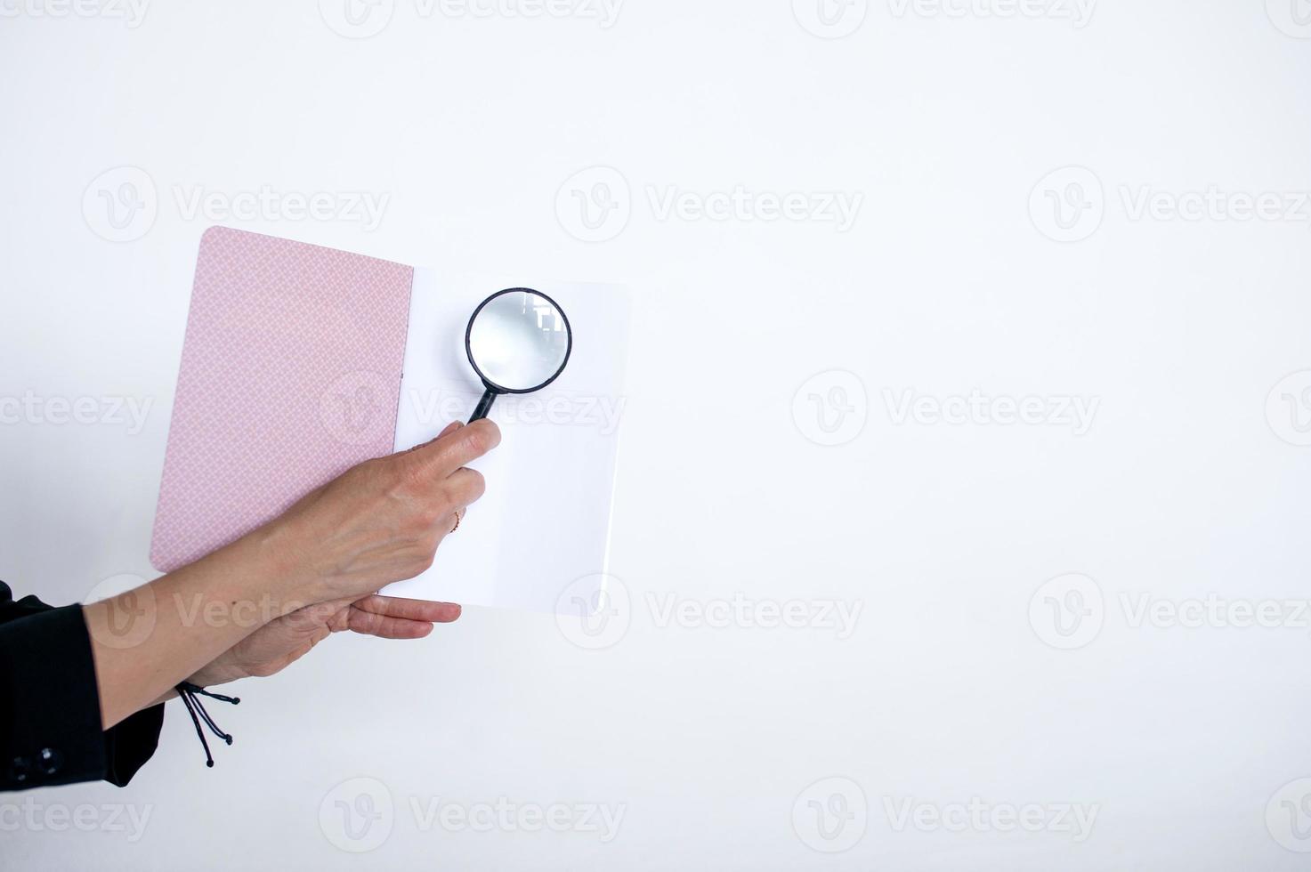 magnifying glass in hand on the background of a notebook photo