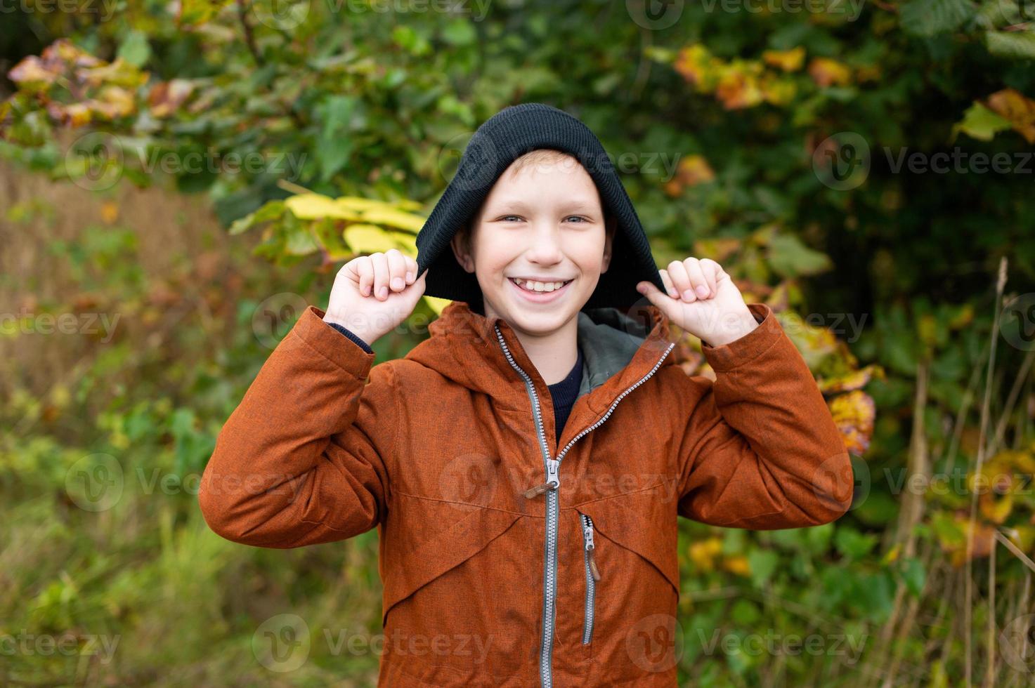 Cute boy in a jacket holding a hat with his hands photo