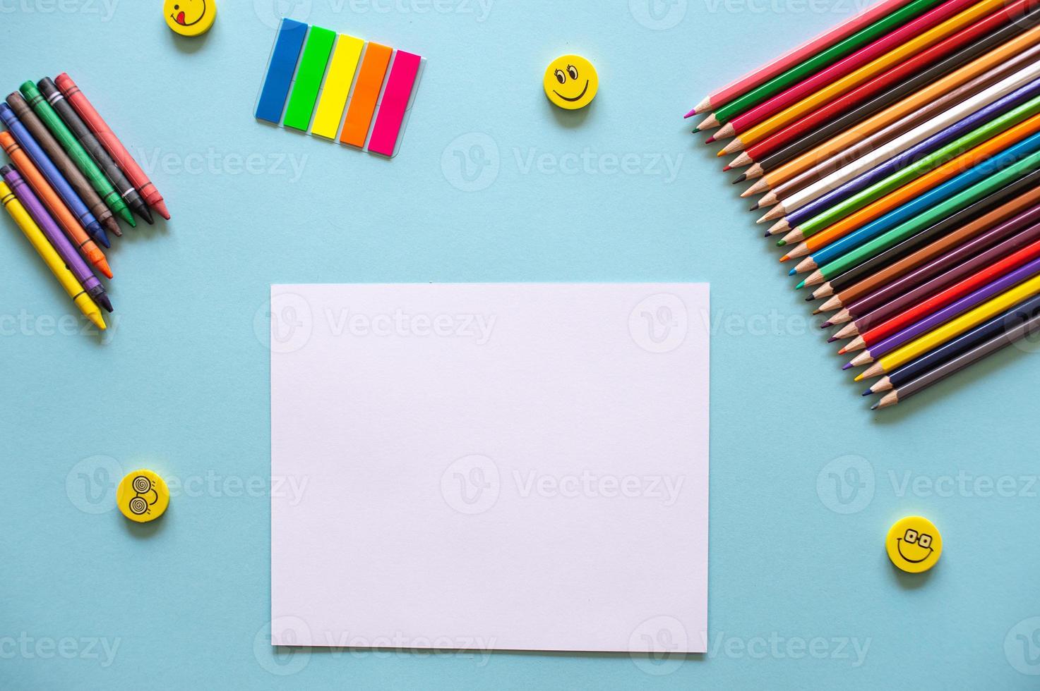 A set of bright stationery items on a blue background. Colored pencils and white paper photo