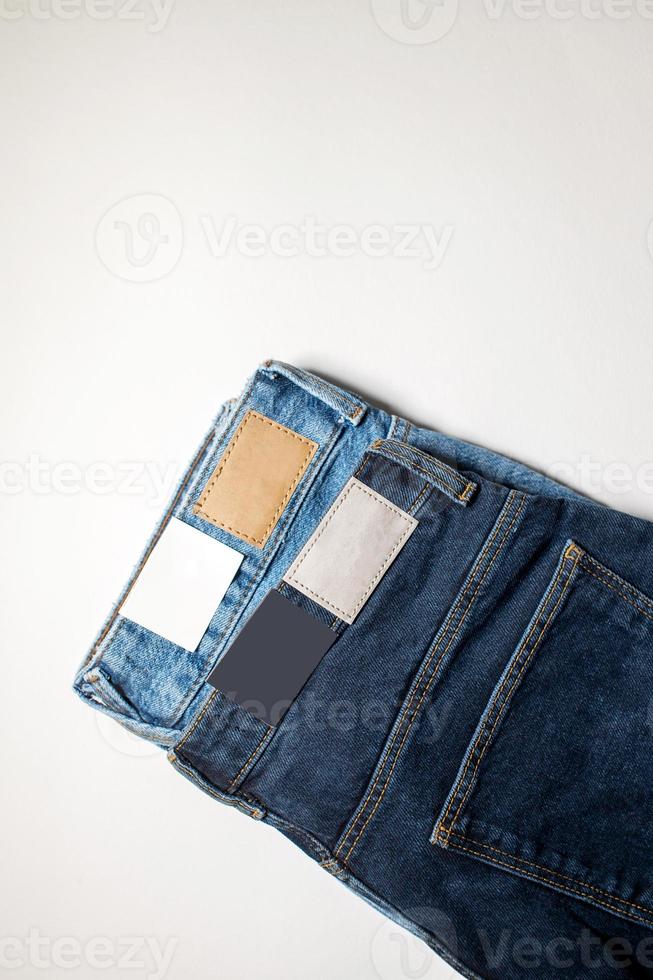 Two pairs of denim trousers in different colors with an empty leather label . photo