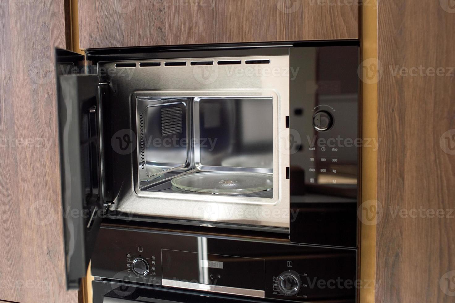 Open built-in microwave oven in wooden kitchen photo