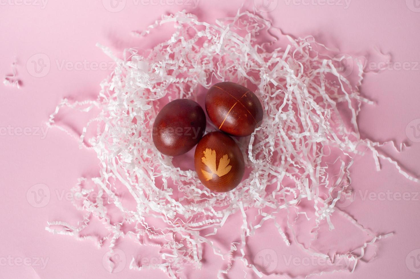 Three framed red eggs with drawings lie in an eco-friendly tray on a pink background photo