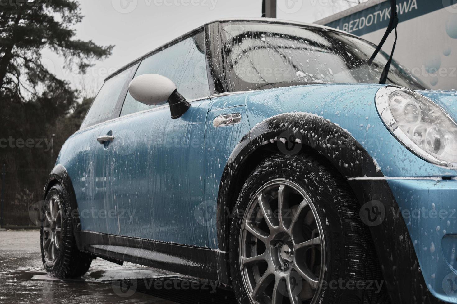 Hand wash with soap, pink foam on the body. Car washing with high pressure water. Wash Mini Cooper. photo