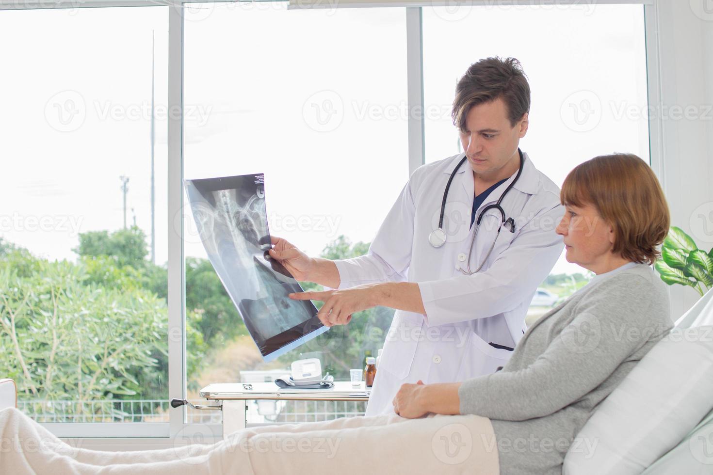 el médico es examinando el paciente en el hospital. caucásico médico vistiendo vestido y escuchando dispositivo demostración radiografía película con un hembra paciente a el hospital foto