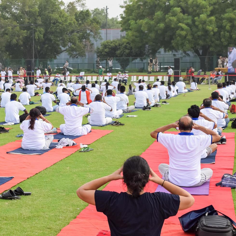 New Delhi, India, June 21 2022 - Group Yoga exercise session for people at Yamuna Sports Complex in Delhi on International Yoga Day, Big group of adults attending yoga class in cricket stadium photo