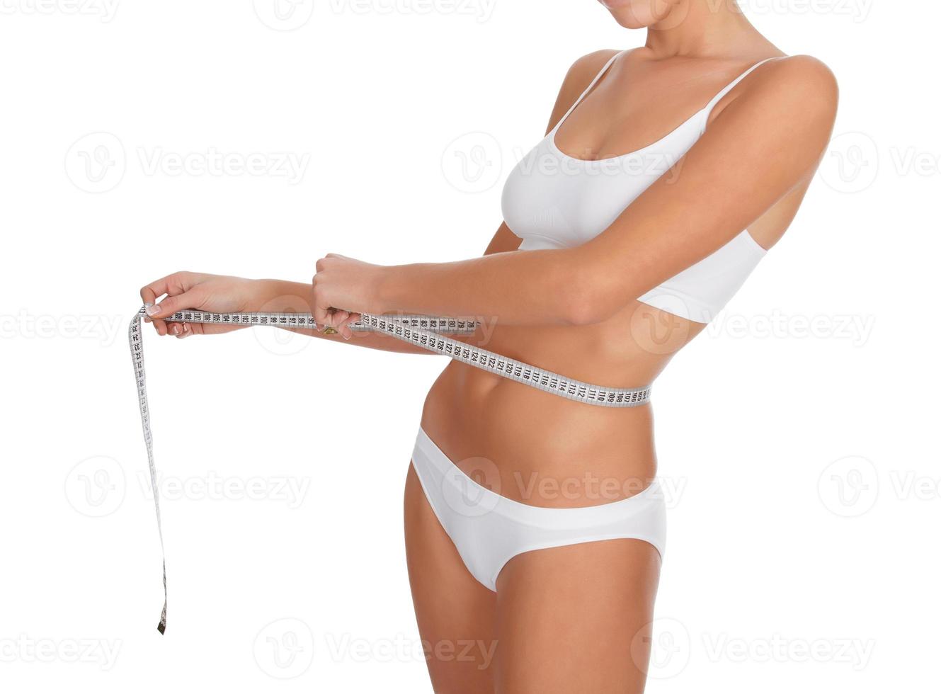 fit young woman measuring her waistline, white background photo