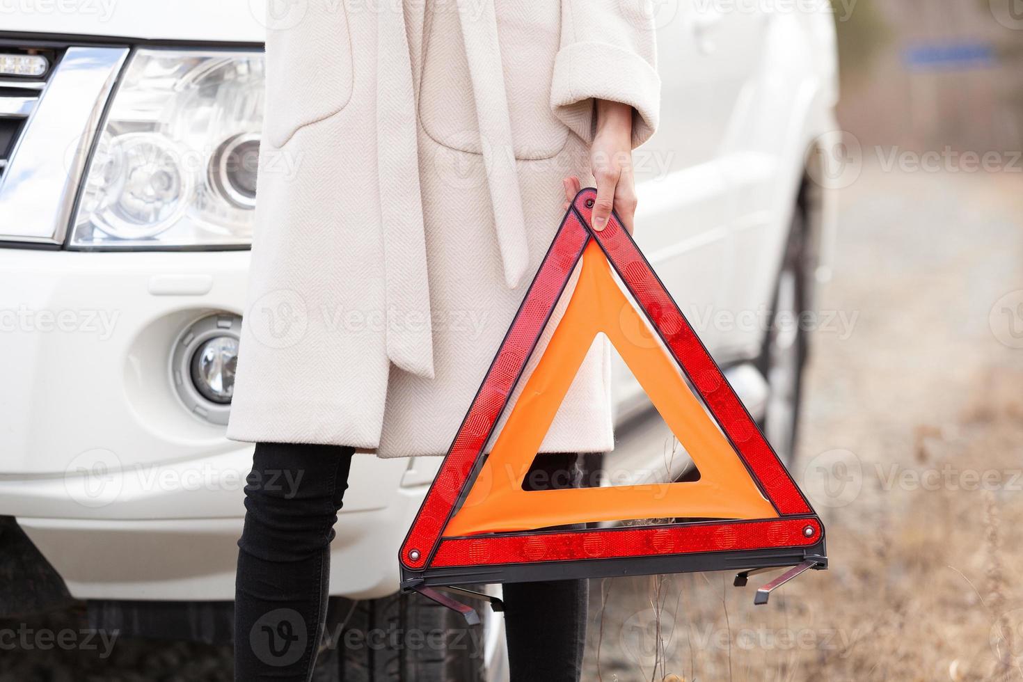 Closeup shot of broken car, girl and warning triangle photo