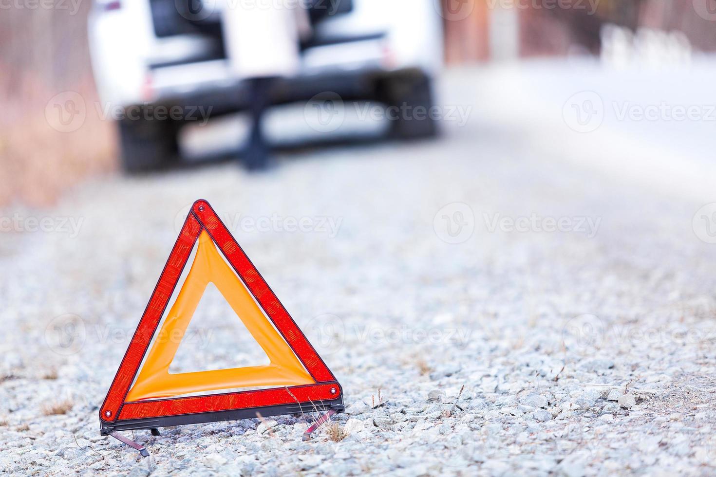 Closeup shot of warning red triangle sign, broken car and girl photo