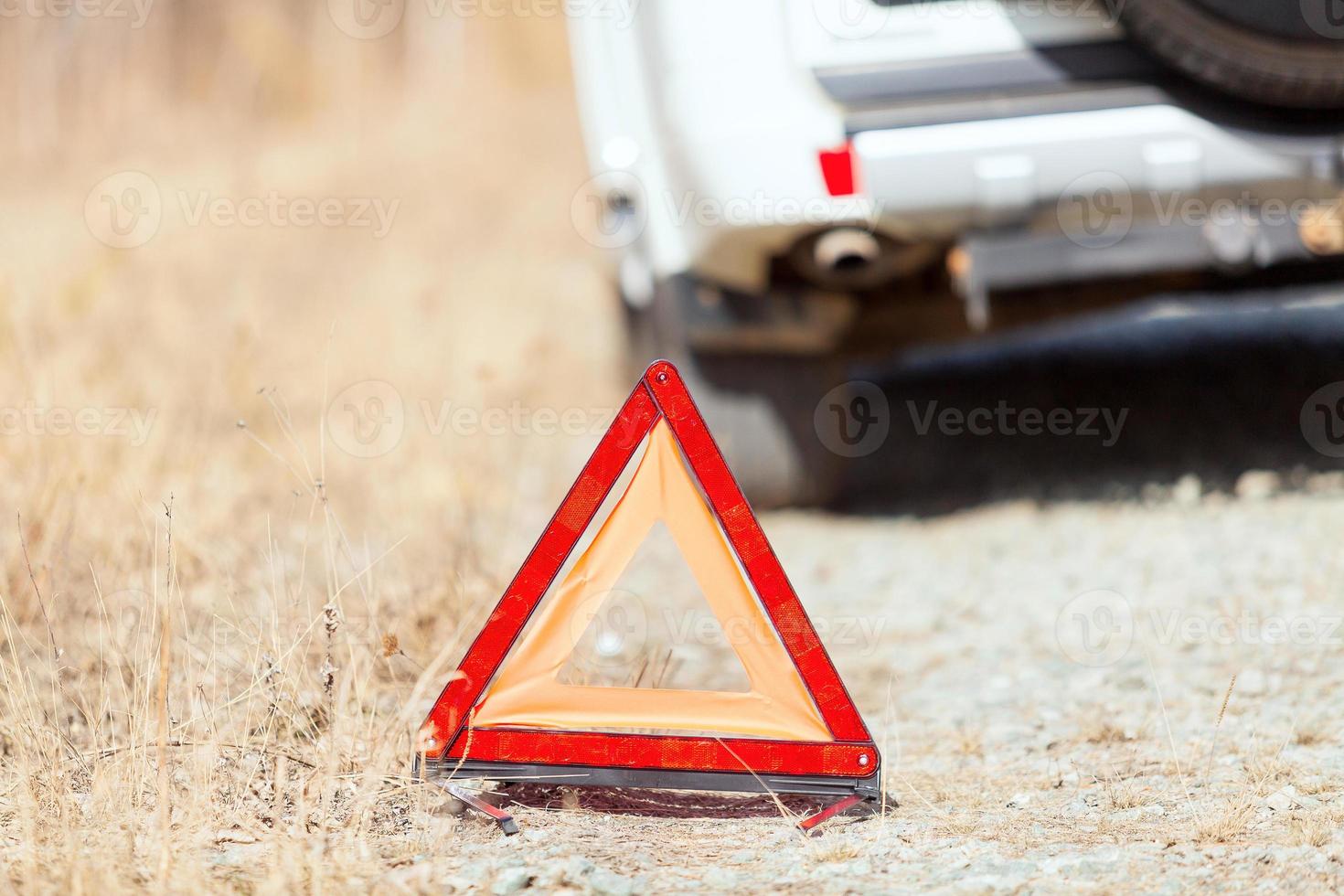 Closeup shot of the red emergency stop sign and broken white car on the roadside photo