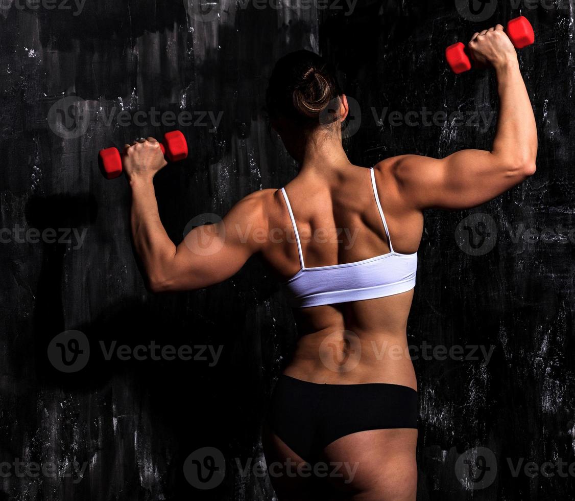 Fitness woman with red dumbbells on a dark background photo