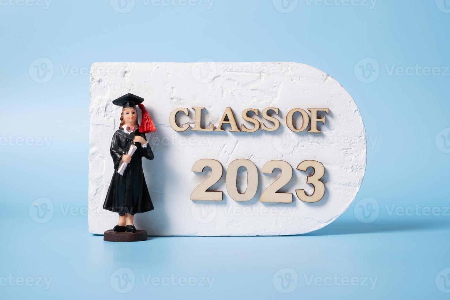 Class of 2023 concept. Wooden number 2023 with graduate statuette on color background photo