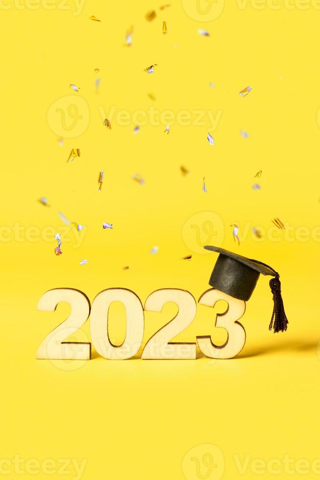 Class of 2023 concept. Wooden number 2023 with graduated cap on colored background photo
