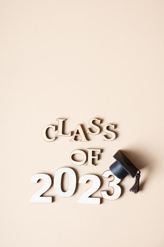 Class of 2023 concept. Wooden number 2023 with graduated cap on beige background. photo