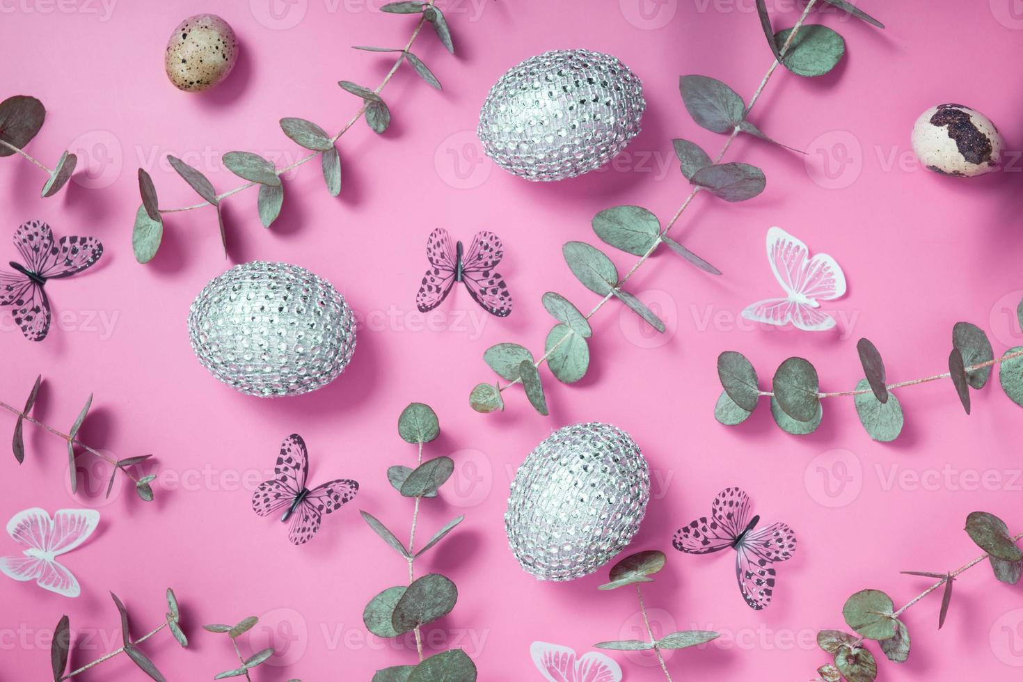 Pattern of Easter eggs, eucalyptus, butterflies and beads. Trendy flat lay composition on color background photo