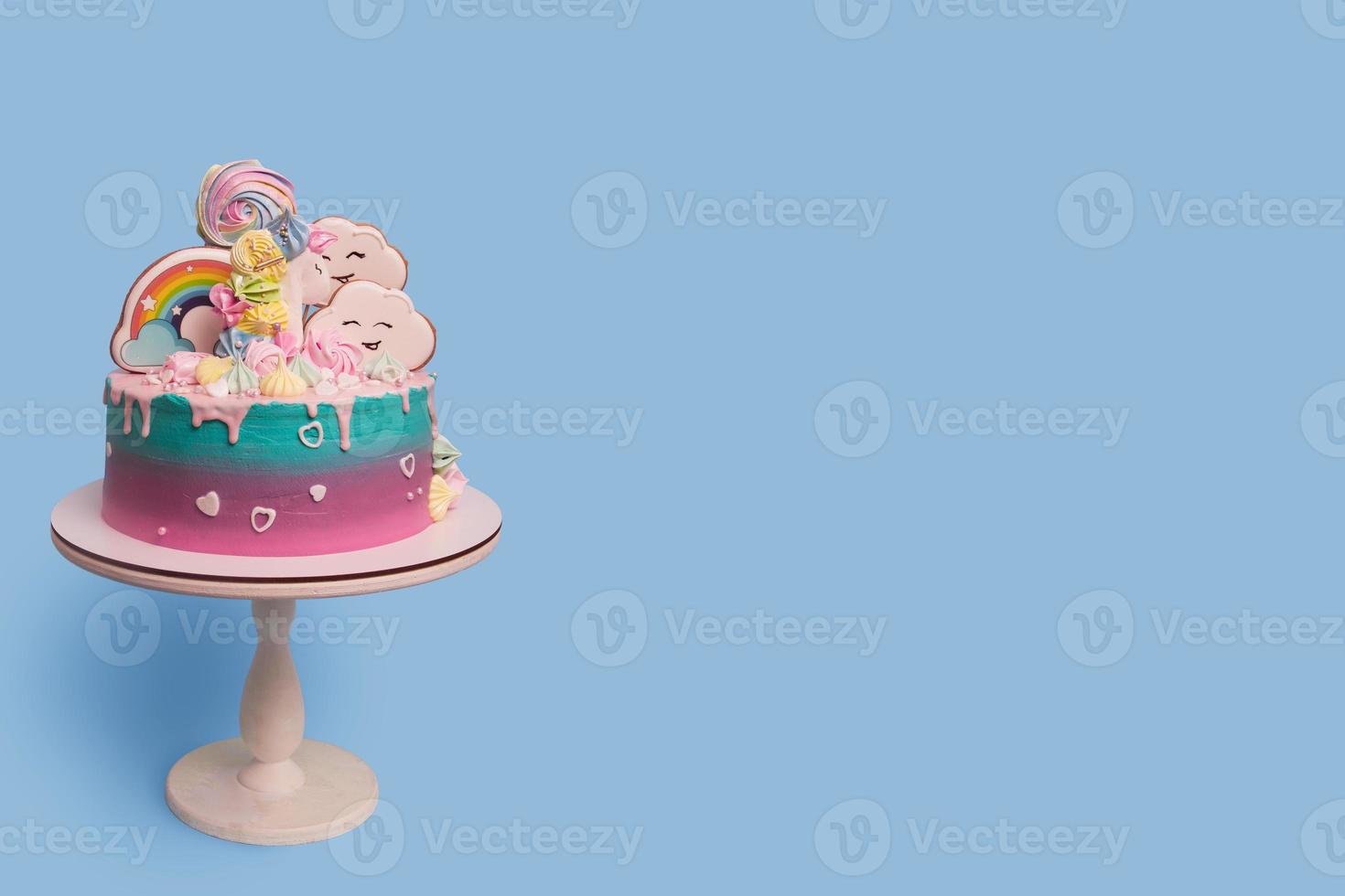 Beautiful festive with unicorn children's cake on a stand on a blue background with copy space photo