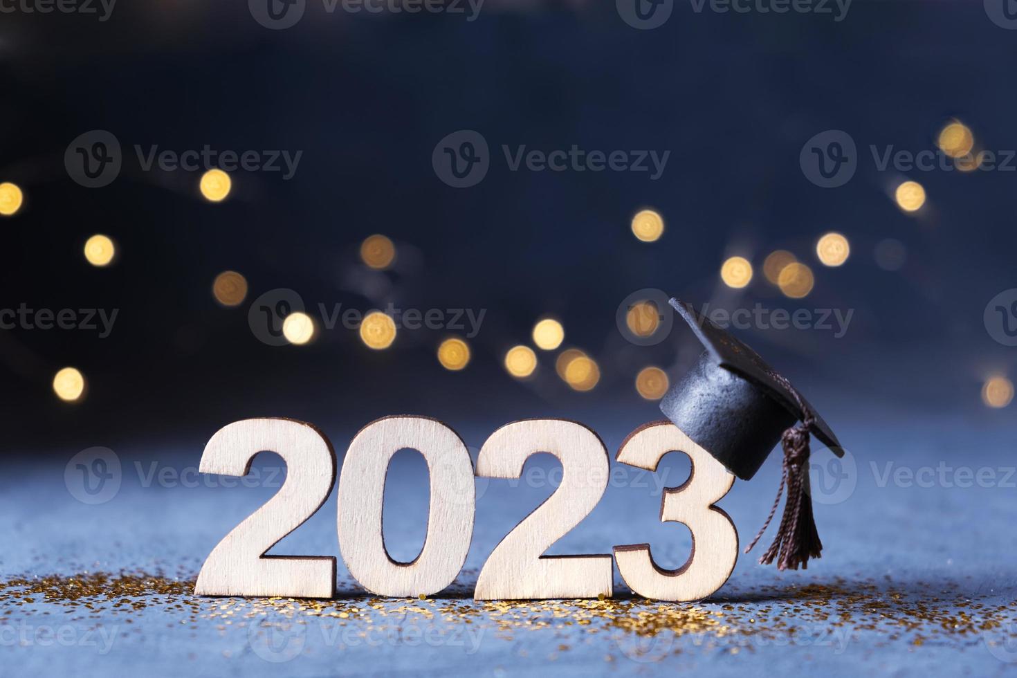 Class of 2023 concept. Wooden number 2023 with graduate hat on dark background with bokeh photo