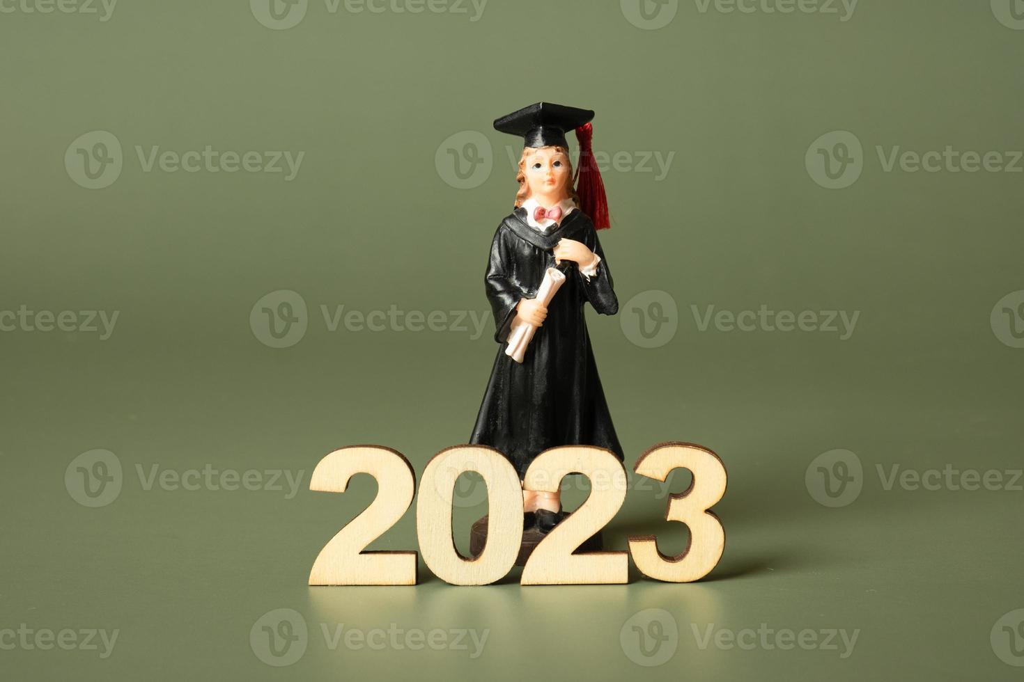 Class of 2023 concept. Wooden number 2023 with graduate statuette on color background photo