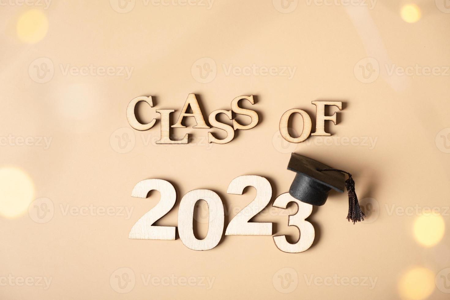 Class of 2023 concept. Wooden number 2023 with graduated cap on beige background with bokeh photo