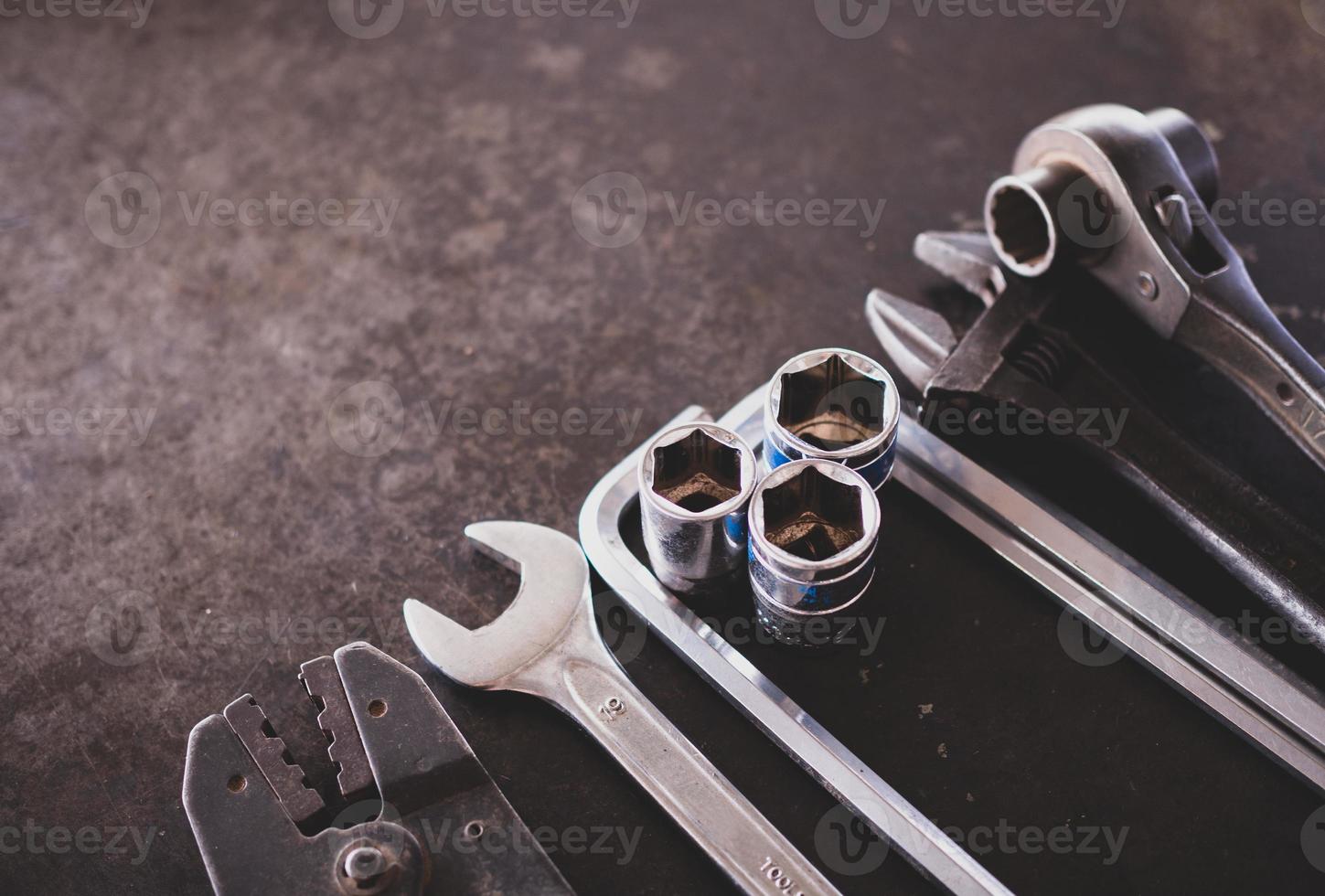 Hand tools consisting of wrenches, pliers, socket wrenches, laid out on old steel plate background. photo