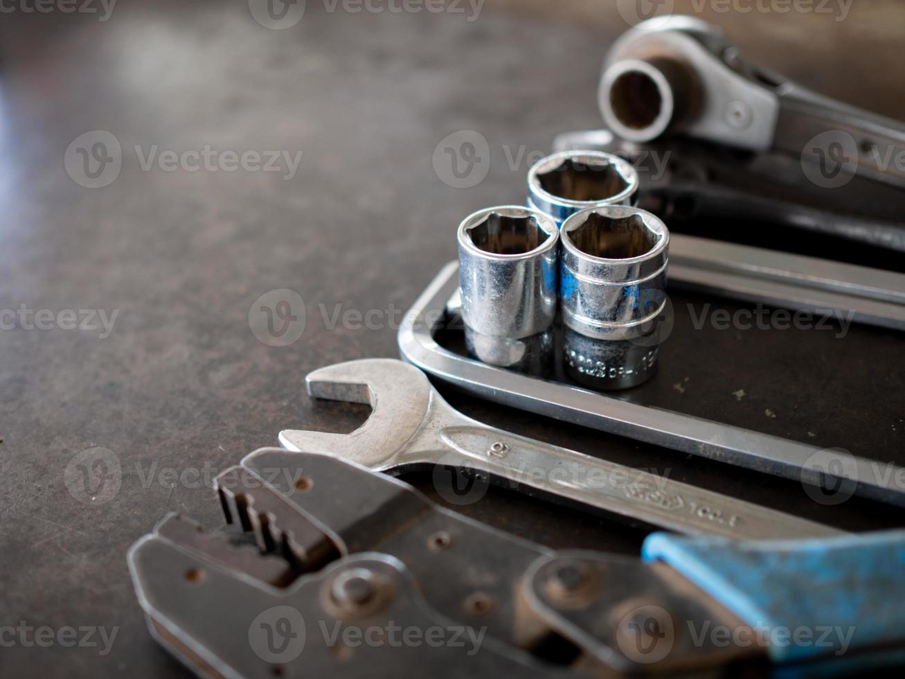 Hand tools consisting of wrenches, pliers, socket wrenches, laid out on old steel plate background. photo