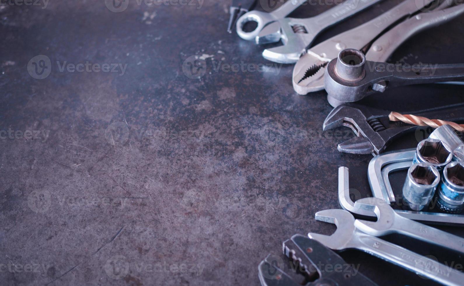 Hand tools consisting of wrenches, pliers, socket wrenches, laid out on old steel plate background. photo