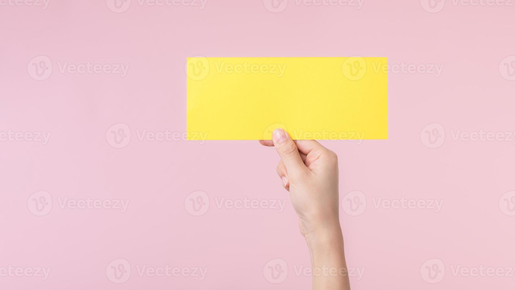 Woman hand holding and showing blank space paper for advertisement information message poster isolated on pink pastel studio background. photo