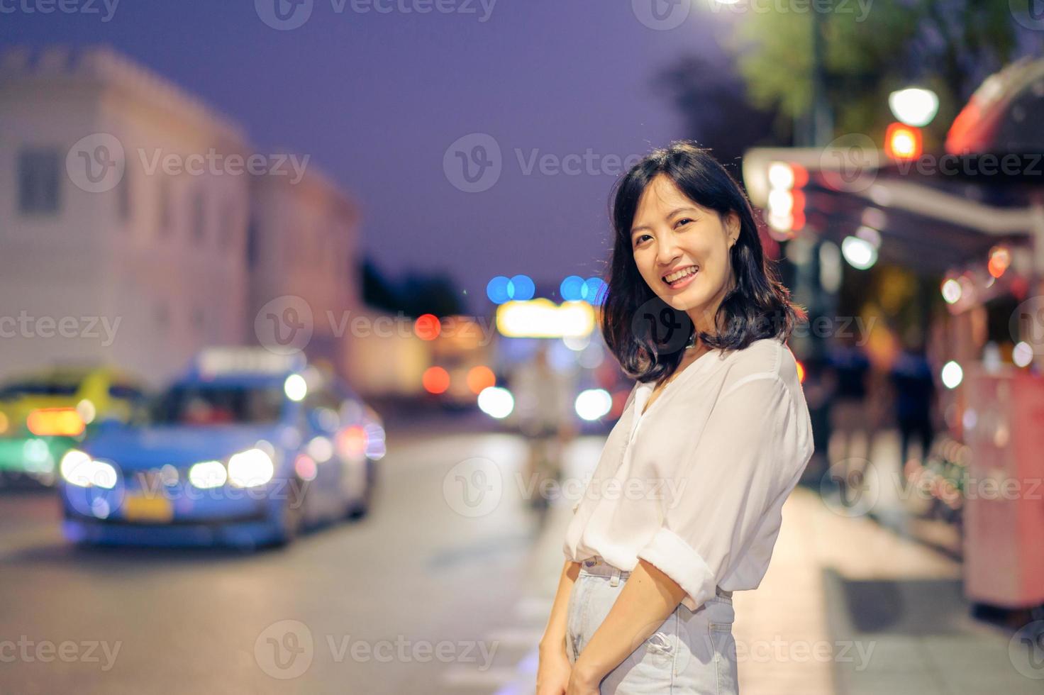 retrato joven hermosa asiático mujer sonriente mientras viaje por el Bangkok calle crepúsculo. foto